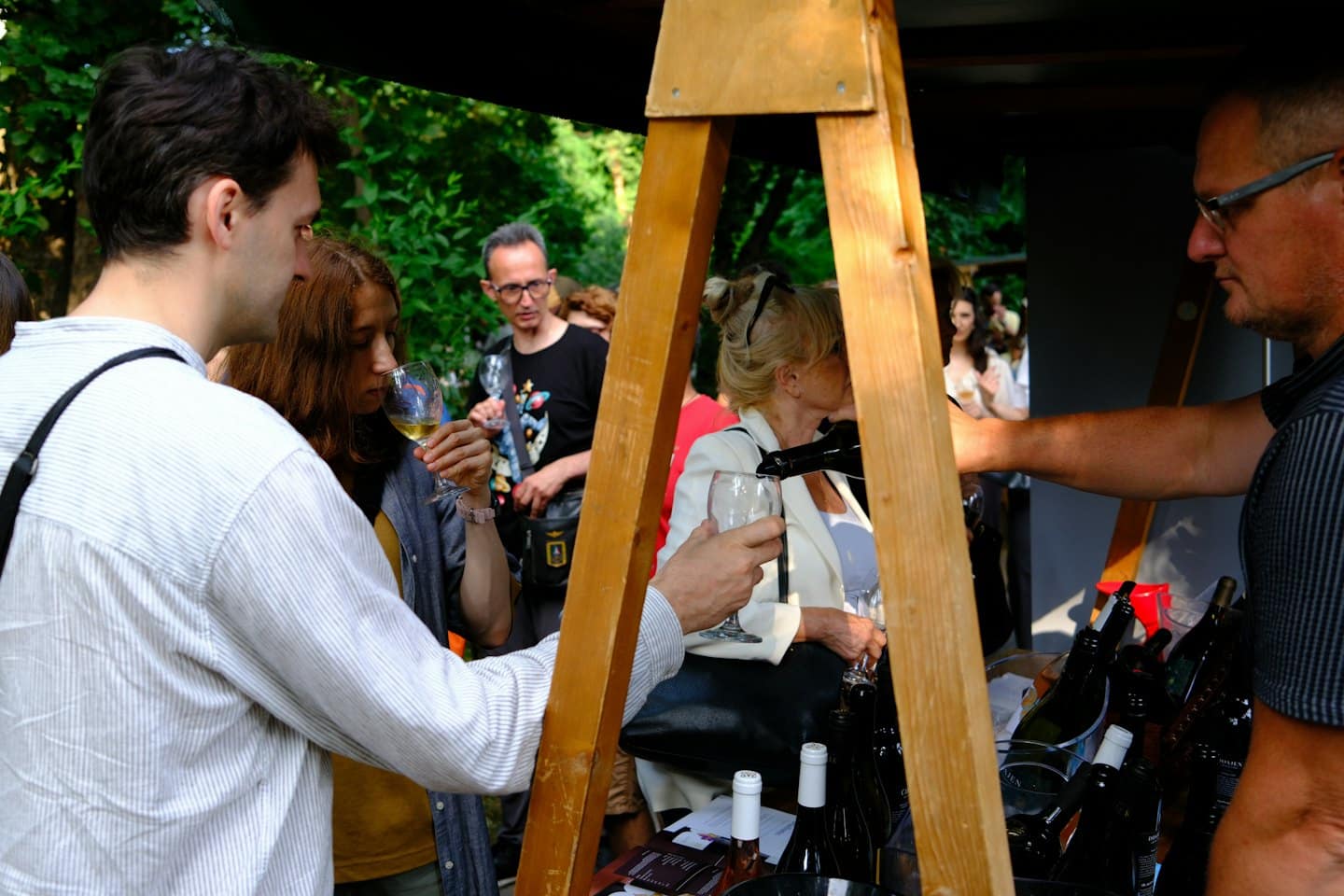 Persone che degustano vino a uno stand rustico all'aperto.